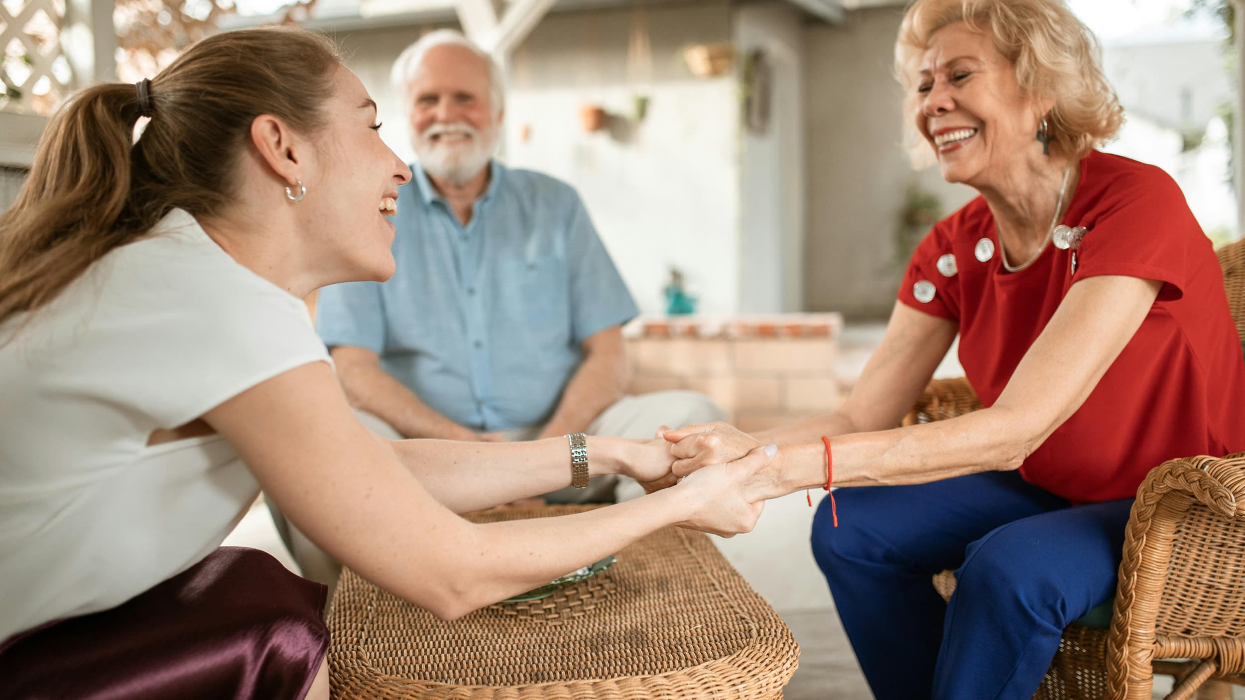 Family members laughing together on a sunny patio